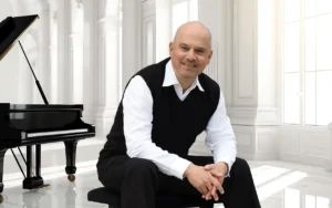 Dinis Schemann vor dem Piano in einem weißen Saal