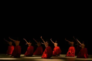 dunkle Bühne mit neuen BalletttänzerInnen in knallroten Reifröcken. Premiere der Ballettfestwoche München Bella Figura